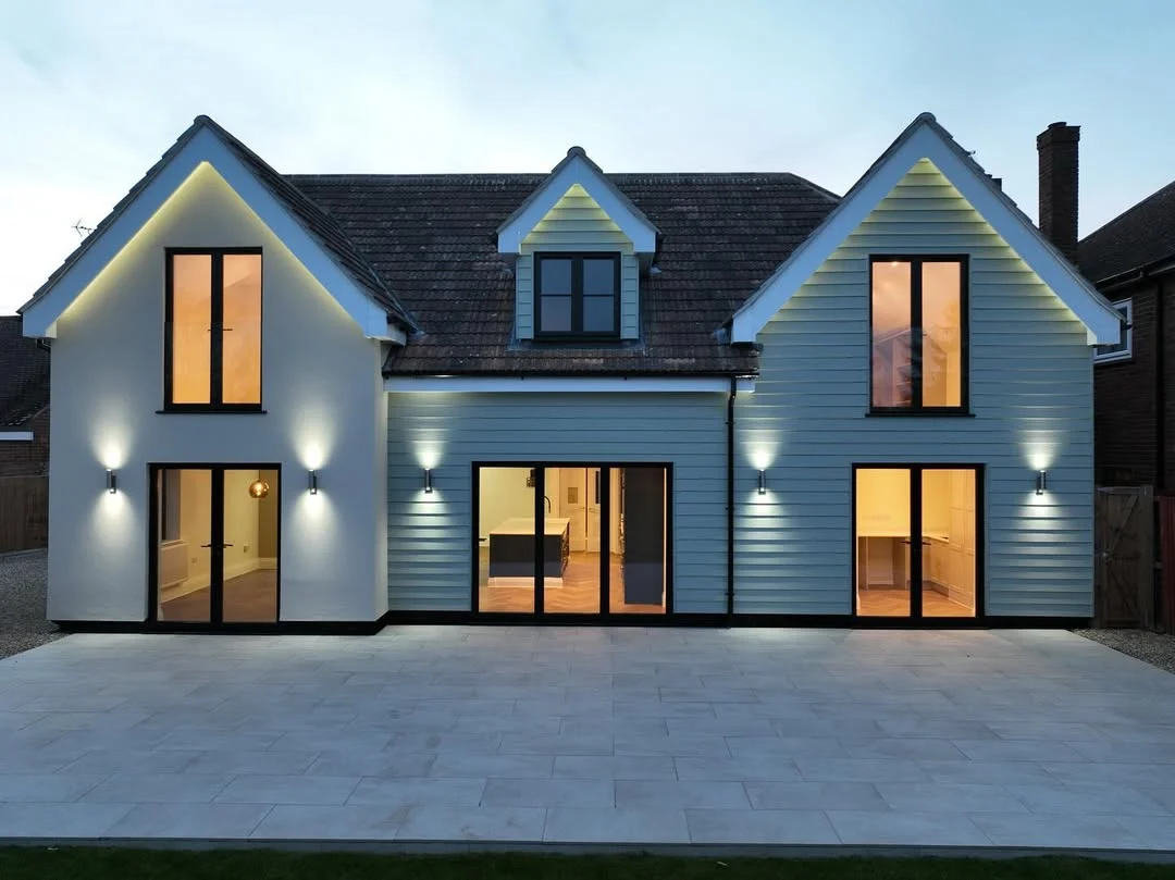 Recently completed Essex home with full-height aluminium bi-fold doors and lit windows at dusk by Bi Folds & Windows Direct